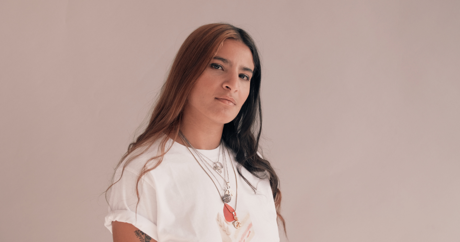 gender equality – blog header A person of colour in a white shirt with necklaces and coloured hair against a neutral background
